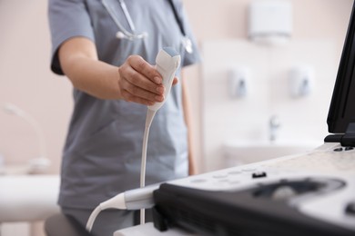 Photo of Sonographer with transducer and ultrasound machine in clinic, closeup