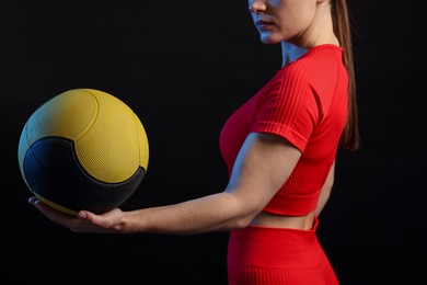 Photo of Woman with medicine ball on black background, closeup
