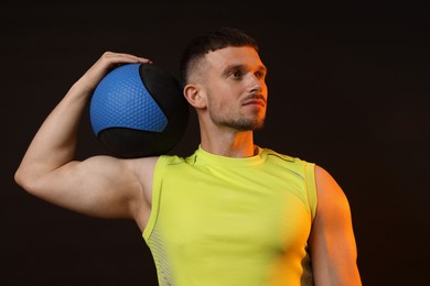 Photo of Man with medicine ball on black background