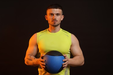 Photo of Man with medicine ball on black background