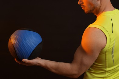 Photo of Man with medicine ball on black background, closeup