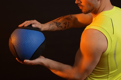 Photo of Man with medicine ball on black background, closeup