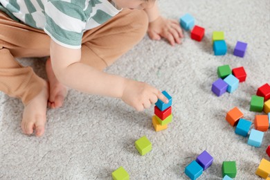 Photo of Cute little child playing with colorful cubes at home, above view
