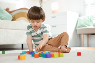 Photo of Cute little child playing with colorful cubes at home. Space for text