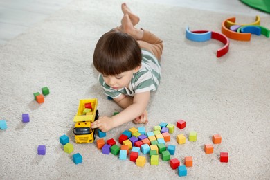 Photo of Cute little child playing with colorful cubes at home