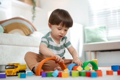 Photo of Cute little child playing with colorful cubes at home
