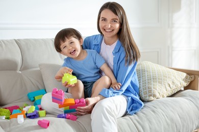 Photo of Mother and son playing with building bricks on sofa at home
