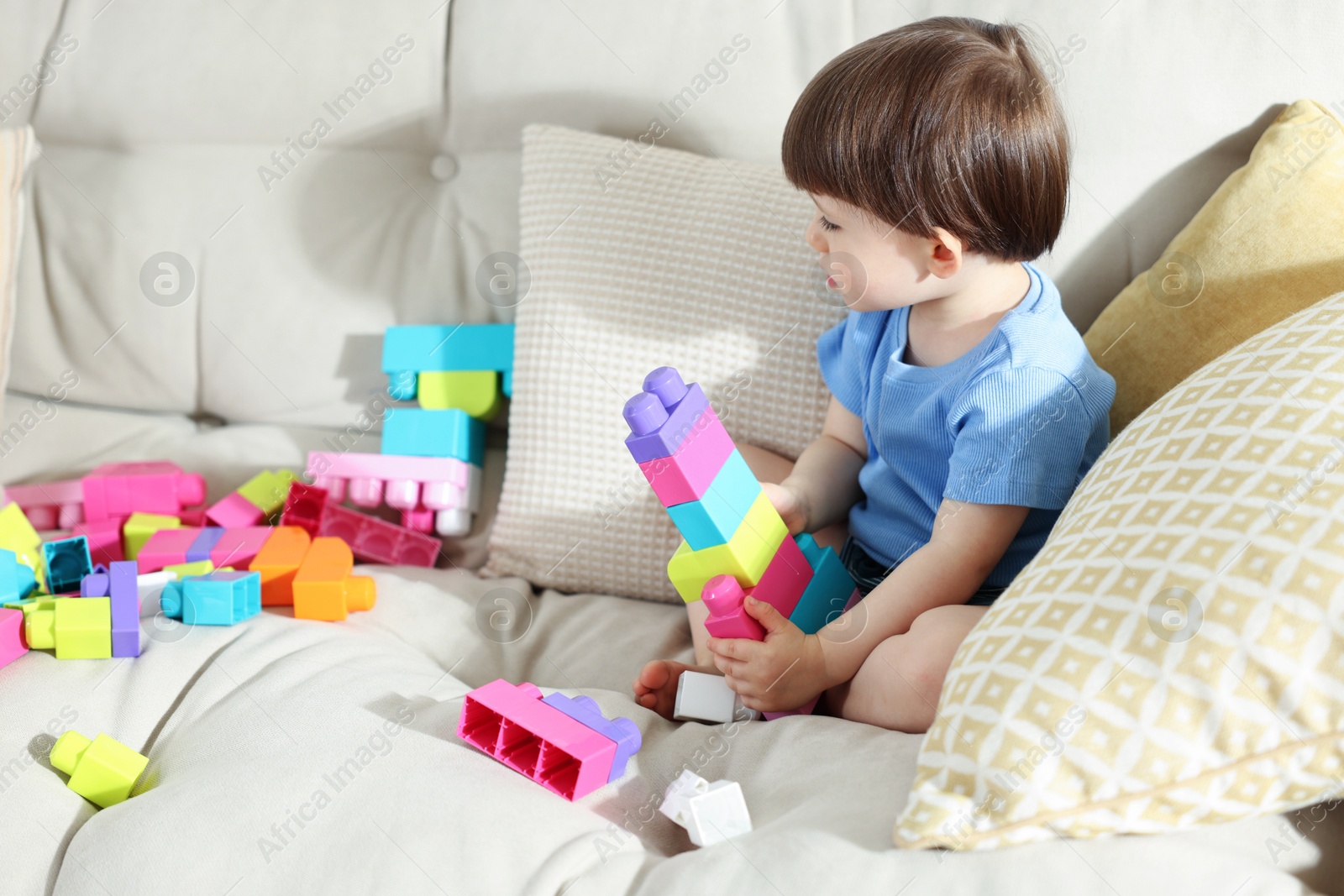 Cute little child playing with building bricks on sofa at home Photo of Cute little child playing with building bricks on sofa at home