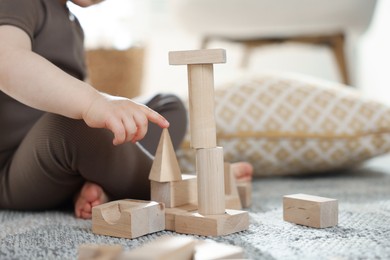 Photo of Cute little child playing with wooden building blocks at home, closeup. Space for text