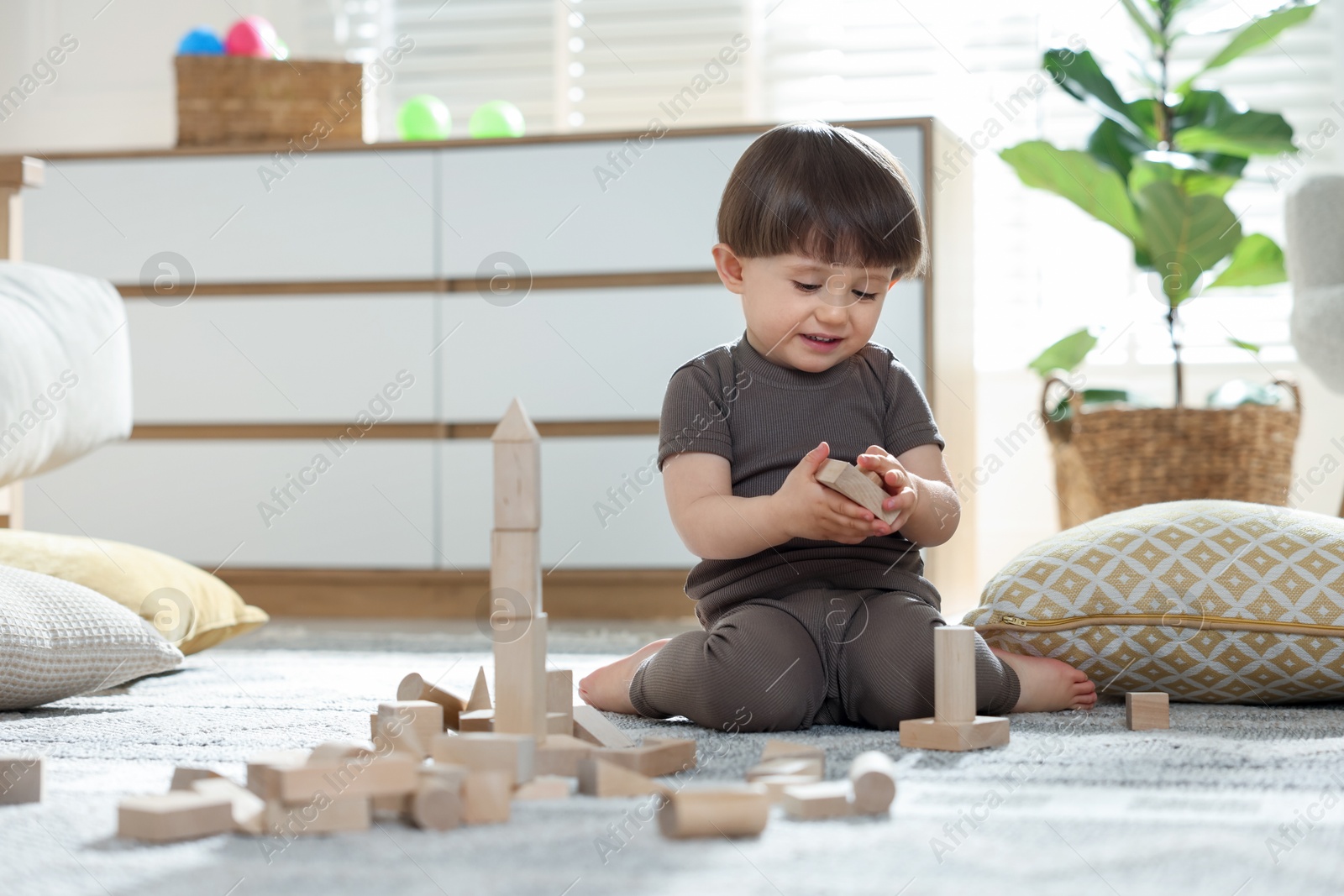 Cute little child playing with wooden building blocks at home. Space for text Photo of Cute little child playing with wooden building blocks at home. Space for text