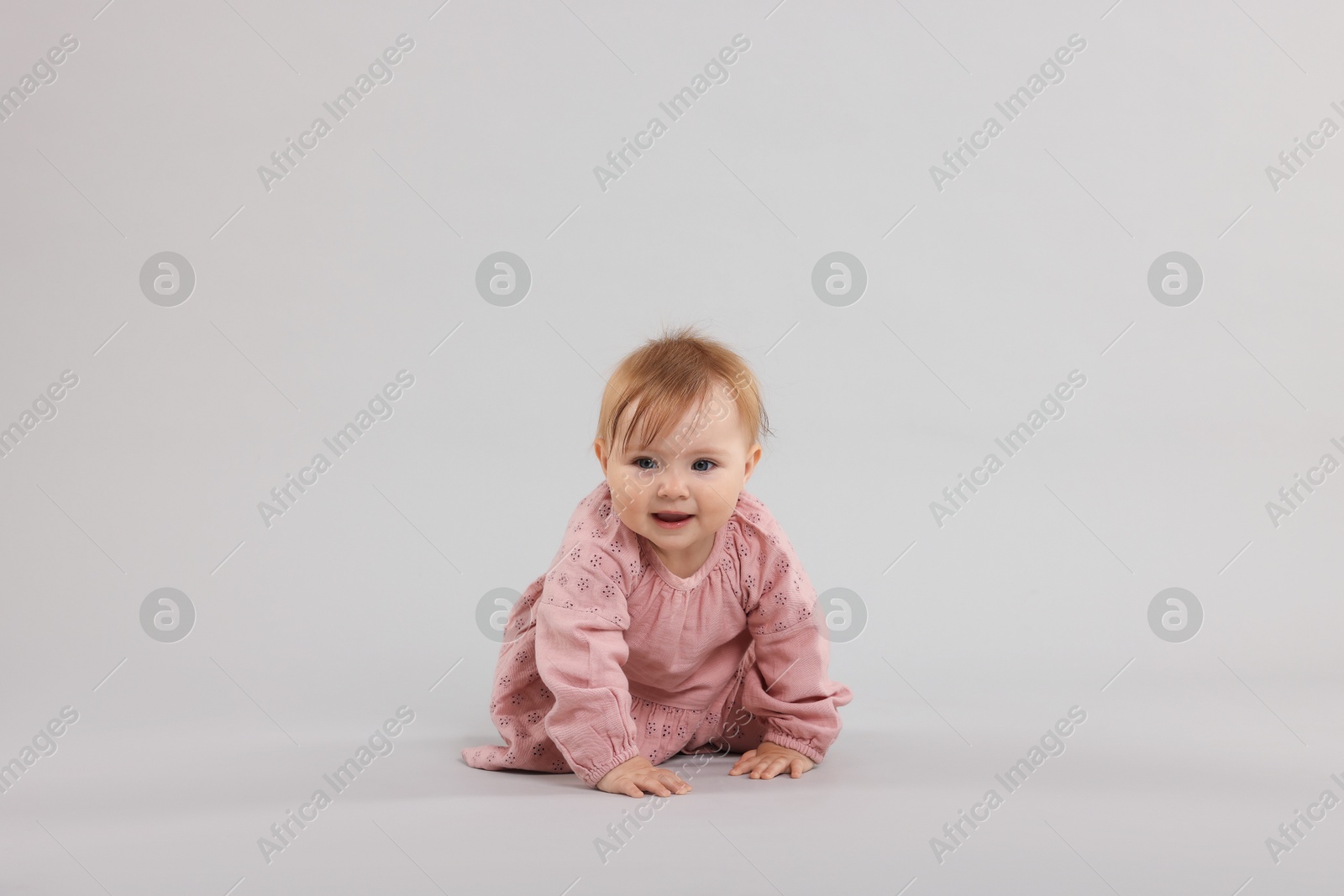Cute little baby crawling on light grey background Photo of Cute little baby crawling on light grey background