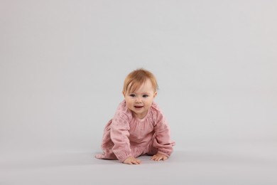 Photo of Cute little baby crawling on light grey background