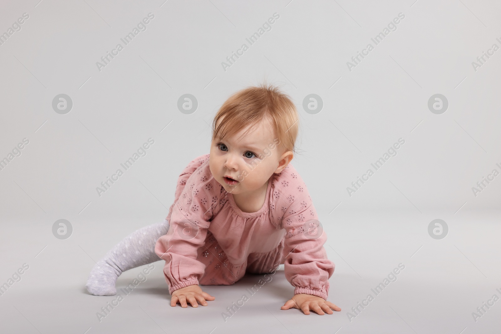Cute little baby crawling on light grey background Photo of Cute little baby crawling on light grey background