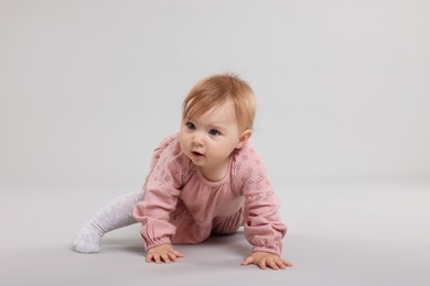 Photo of Cute little baby crawling on light grey background