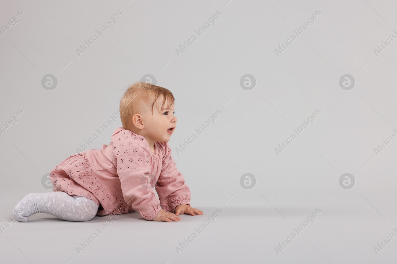 Cute little baby crawling on light grey background, space for text Photo of Cute little baby crawling on light grey background, space for text