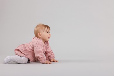 Photo of Cute little baby crawling on light grey background, space for text
