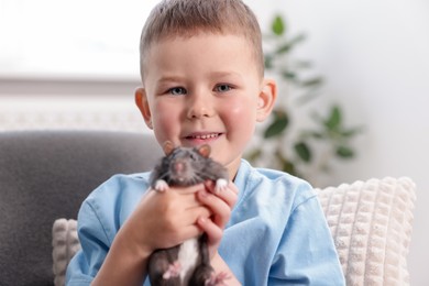 Photo of Little boy with his pet rat on sofa at home