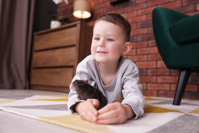 Photo of Little boy with his pet rat on floor at home
