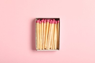 Photo of Matches in box on pink background, top view