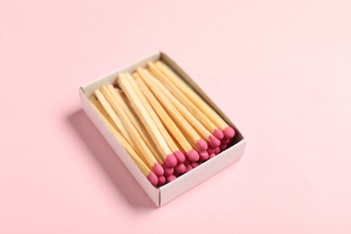 Photo of Matches in box on pink background, closeup