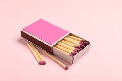 Photo of Matches and box on pink background, closeup