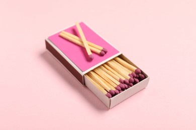 Photo of Matches and box on pink background, closeup
