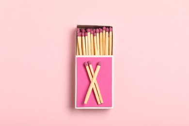 Photo of Matches and box on pink background, top view