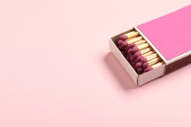 Photo of Matches in box on pink background, closeup. Space for text