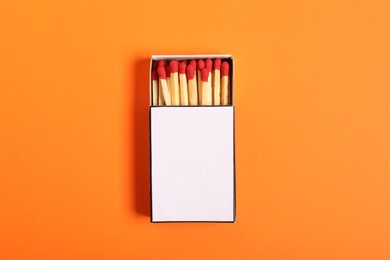 Photo of Matches in box on orange background, top view. Mockup for design