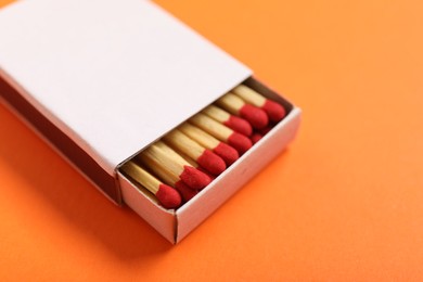 Photo of Matches in box on orange background, closeup. Mockup for design