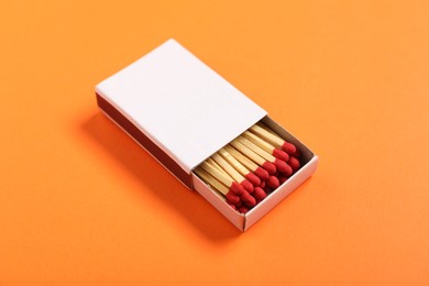 Photo of Matches in box on orange background, closeup. Mockup for design