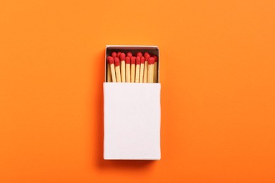 Photo of Matches in box on orange background, top view. Mockup for design