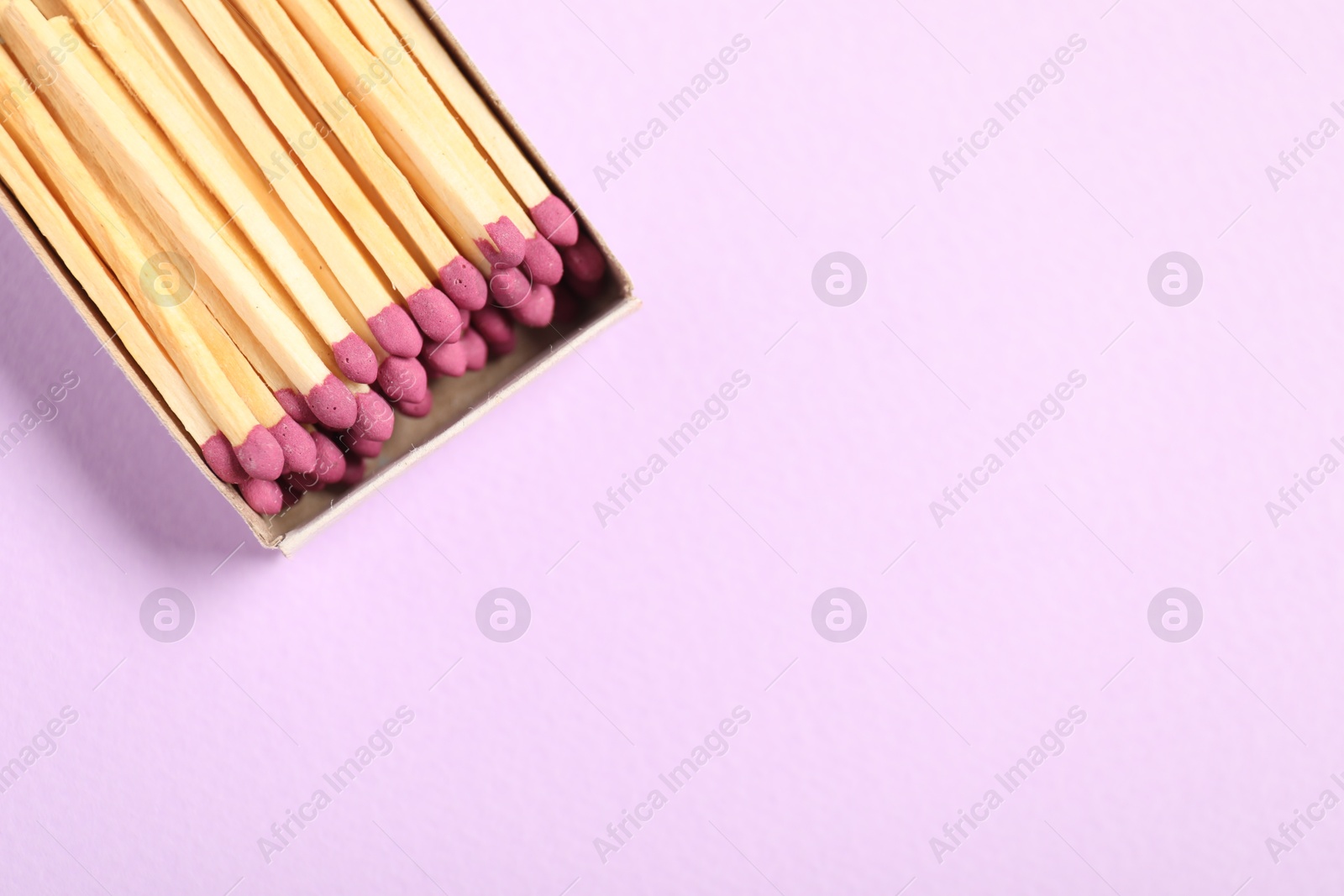 Matches in open box on violet background, top view. Space for text Photo of Matches in open box on violet background, top view. Space for text