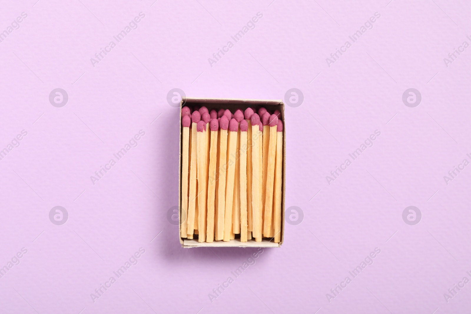 Matches in open box on violet background, top view Photo of Matches in open box on violet background, top view
