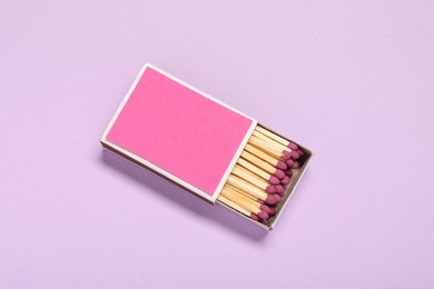 Photo of Matches in box on violet background, top view. Mockup for design
