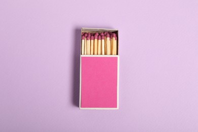 Photo of Matches in box on violet background, top view. Mockup for design