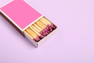 Photo of Matches in box on violet background, closeup. Mockup for design