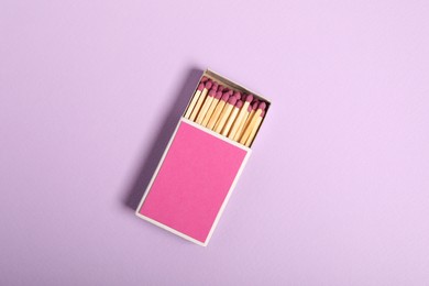 Photo of Matches in box on violet background, top view. Mockup for design