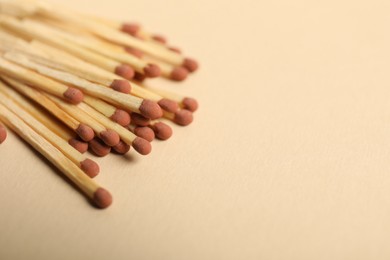 Photo of Matches with brown heads on beige background, closeup. Space for text