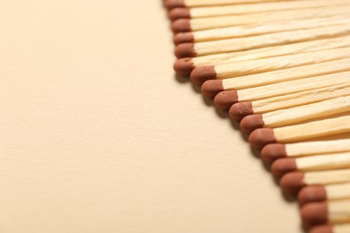 Photo of Matches with brown heads on beige background, closeup. Space for text