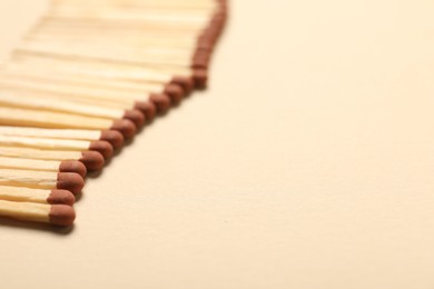 Photo of Matches with brown heads on beige background, closeup. Space for text