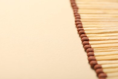 Photo of Matches with brown heads on beige background, closeup. Space for text