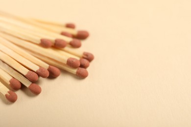 Photo of Matches with brown heads on beige background, closeup. Space for text