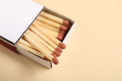 Photo of Matches in box on beige background, closeup. Space for text