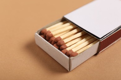 Photo of Matches in box on beige background, closeup