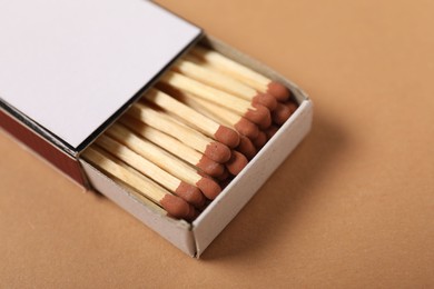 Photo of Matches in box on beige background, closeup