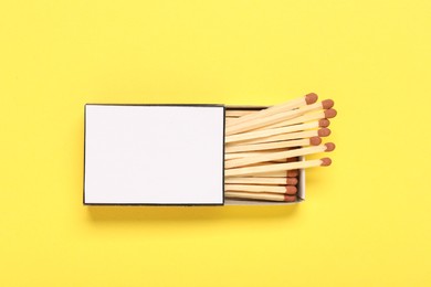 Photo of Matches in box on yellow background, top view. Mockup for design
