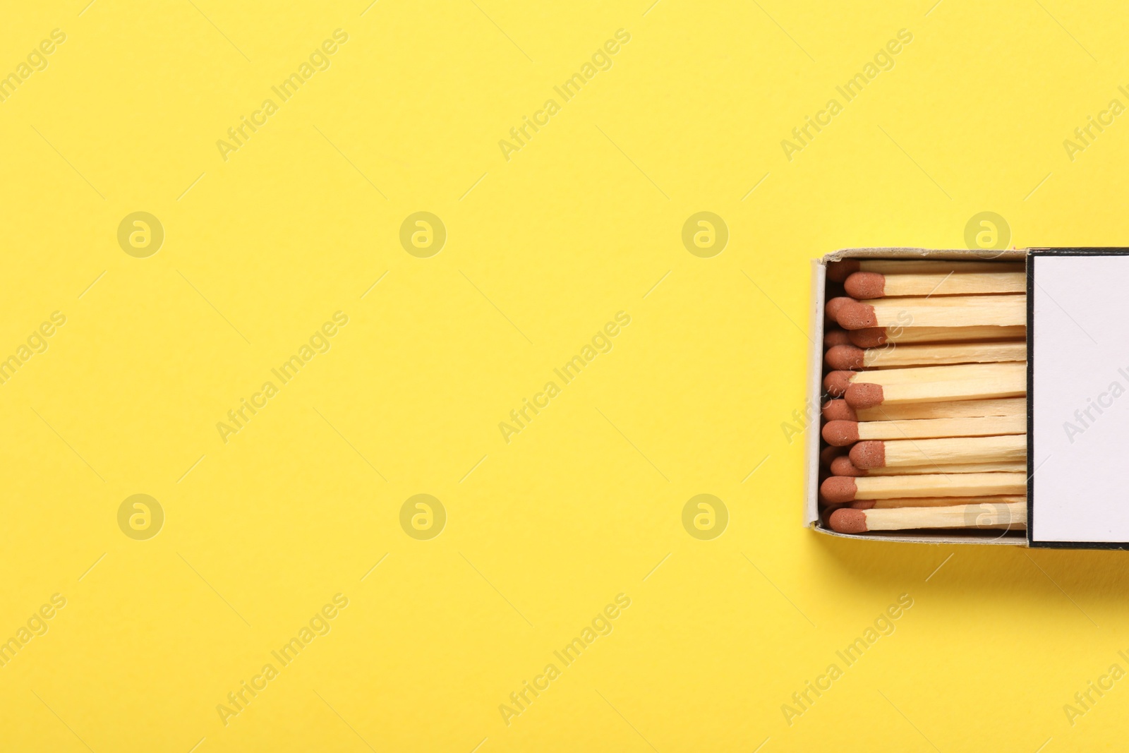 Matches in box on yellow background, top view. Space for text Photo of Matches in box on yellow background, top view. Space for text