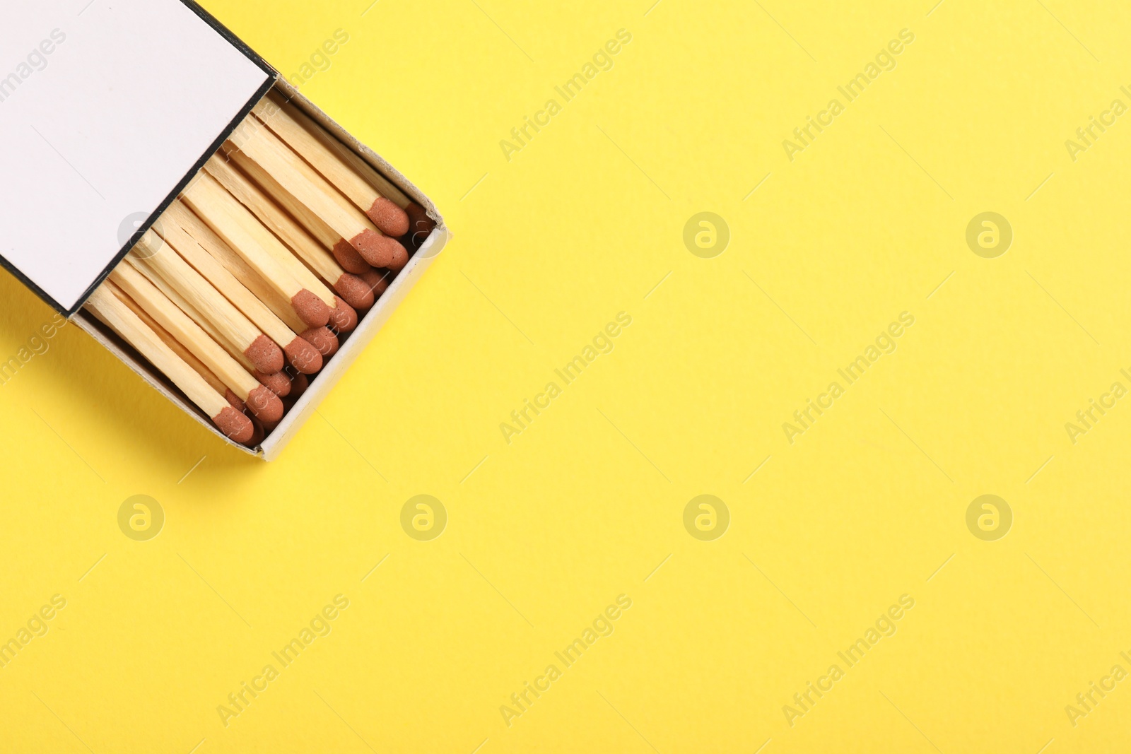 Matches in box on yellow background, top view. Space for text Photo of Matches in box on yellow background, top view. Space for text
