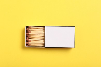 Photo of Matches in box on yellow background, top view. Mockup for design